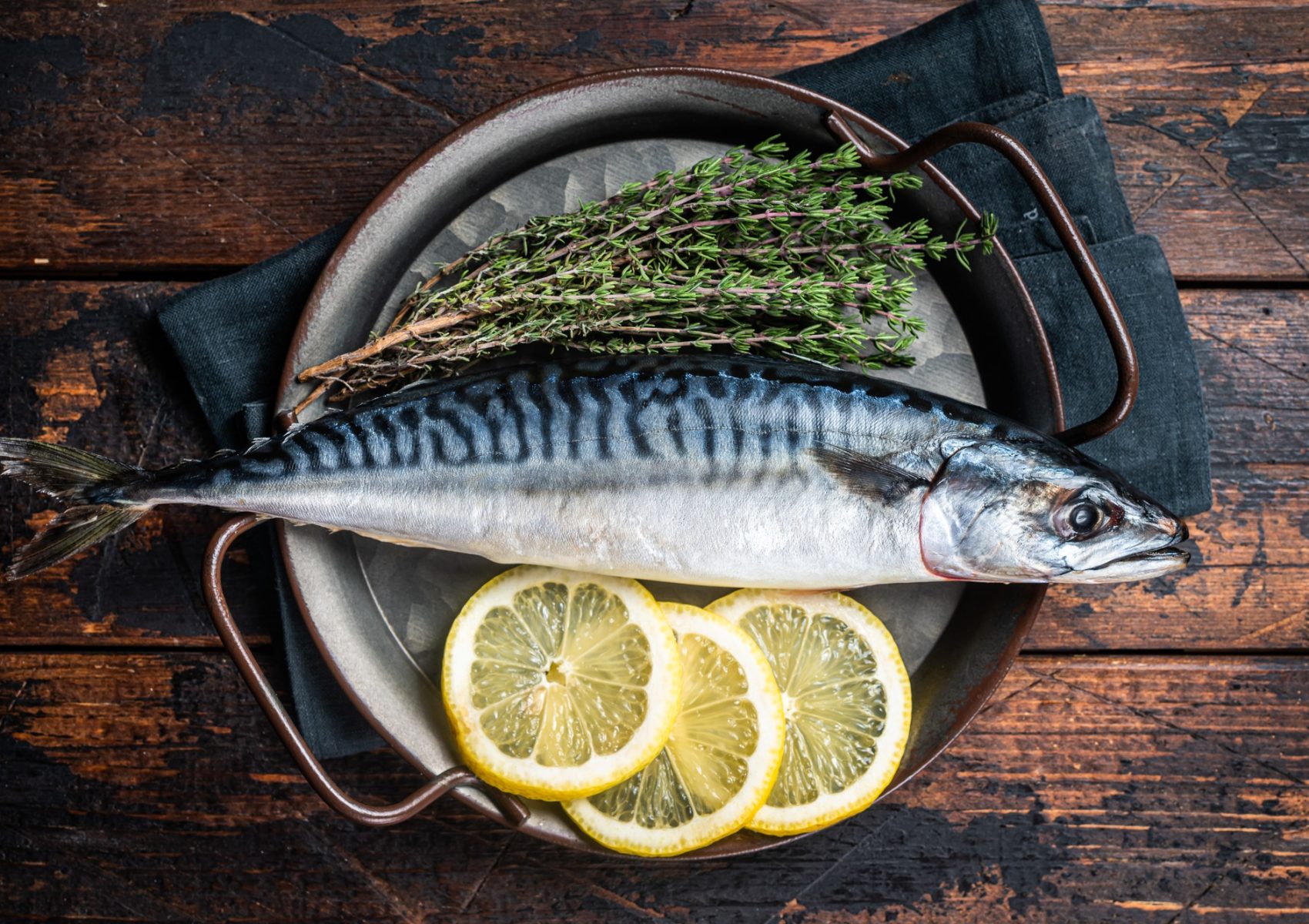 Uncooked mackerel fish, raw scomber with herbs. Wooden background. Top view